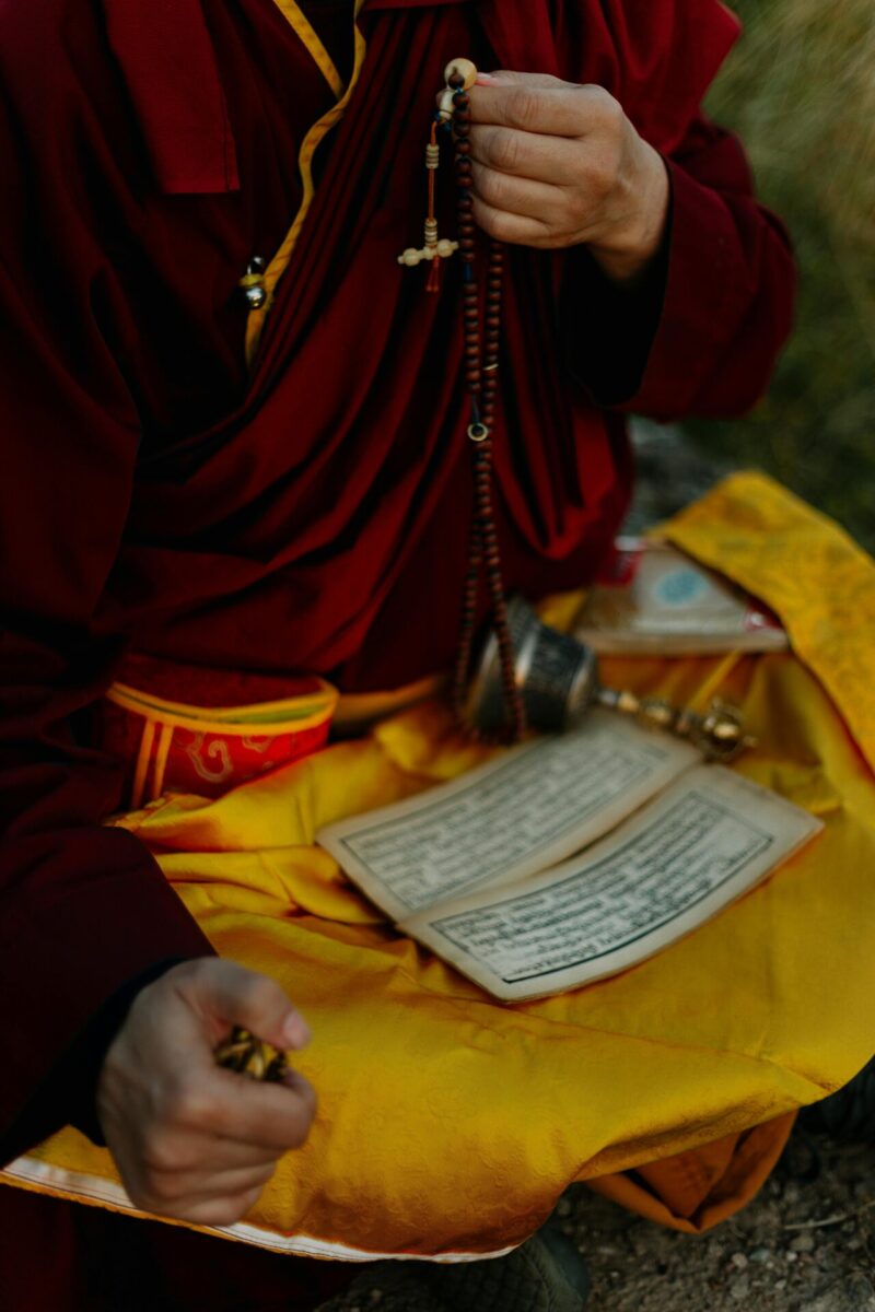 Tibetan monk praying with mala beads, emphasizing spirituality and Tibetan culture.